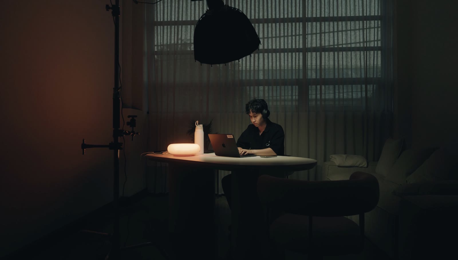 A dark studio, a laptop under a softbox with a warm lamp behind it.